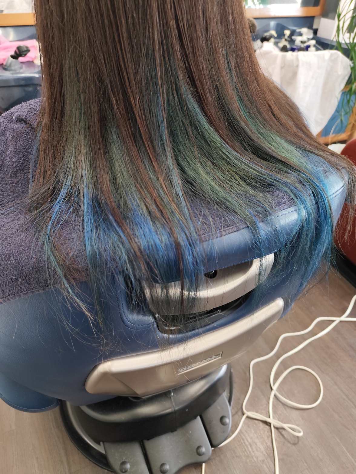 Blue accent highlights in long brown hair at salon